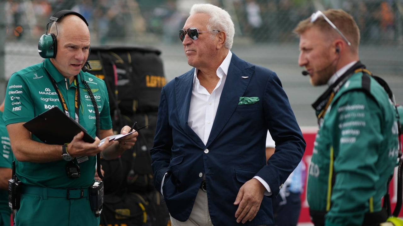 Un team di ingegneri e manager discutono le strategie per migliorare la performance in Formula 1, con enfasi sulla collaborazione e la pazienza